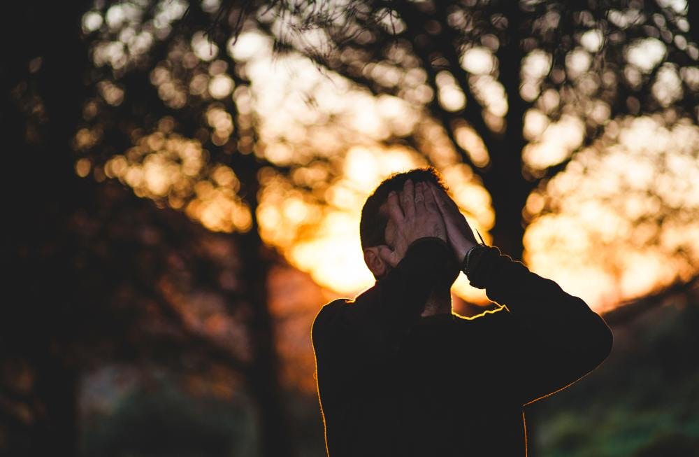 Guy feeling overwhelmed outside in a forest