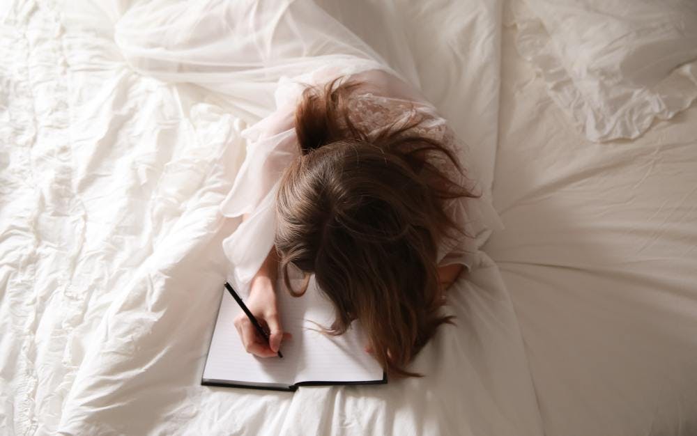 Women journaling on a bed